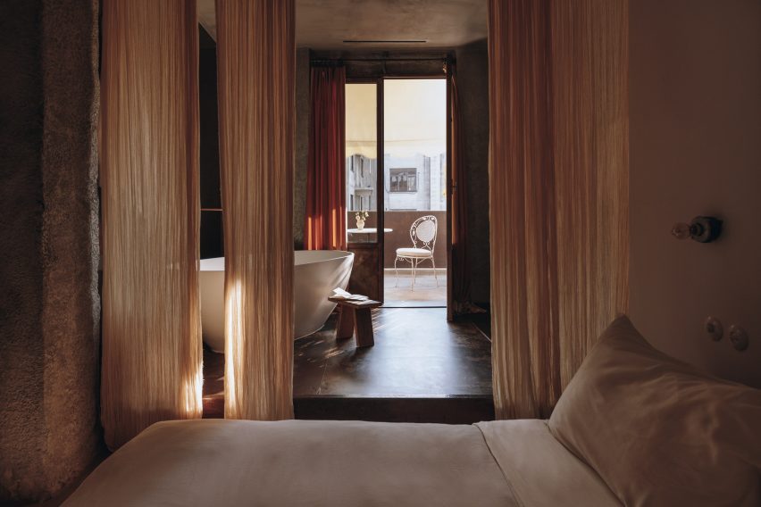 Dark, red-toned bedroom in the Mona hotel in Athens with a freestanding bath