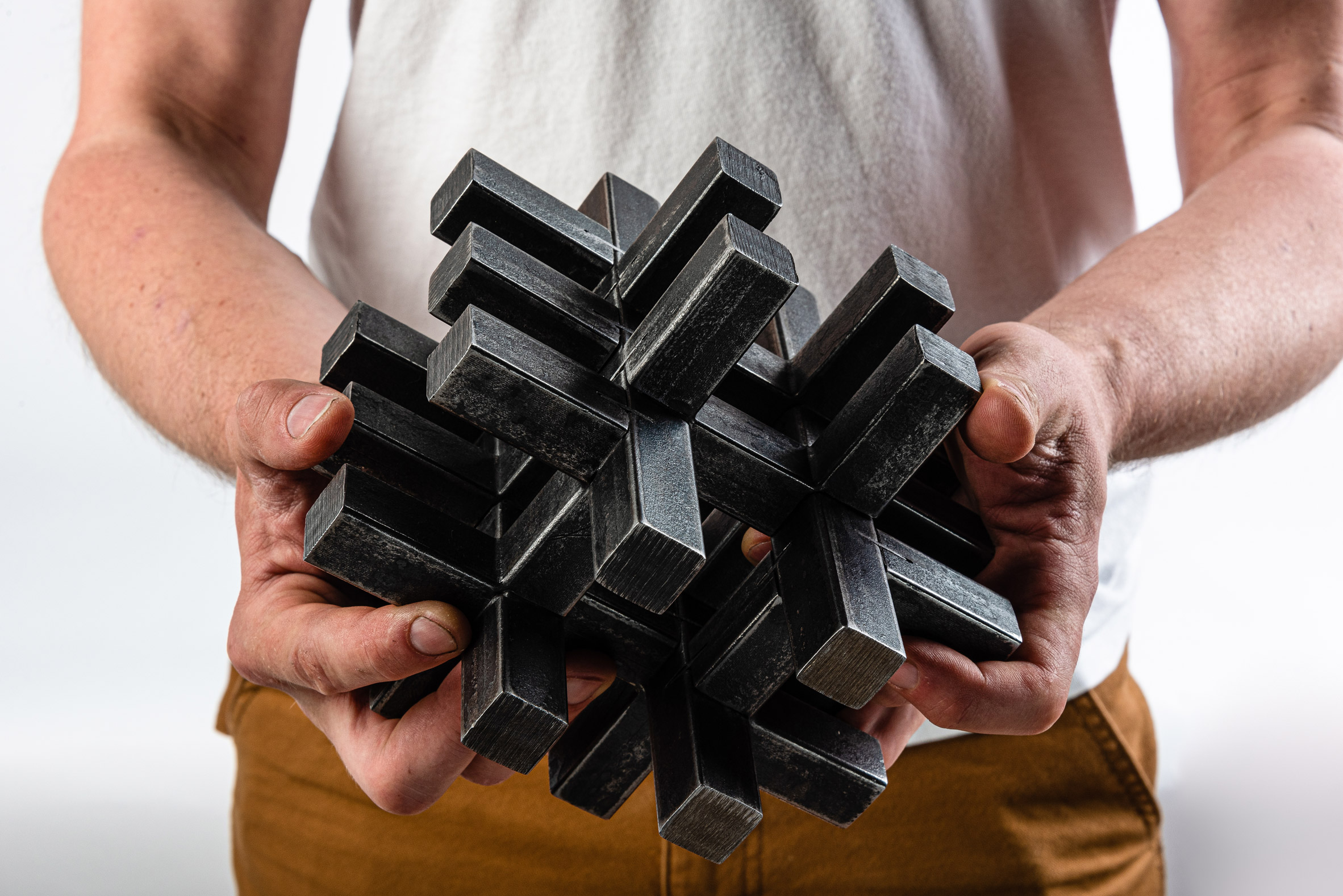 Person holding a black sculpture made up of interlocking 3D crosses by a New Designers winner