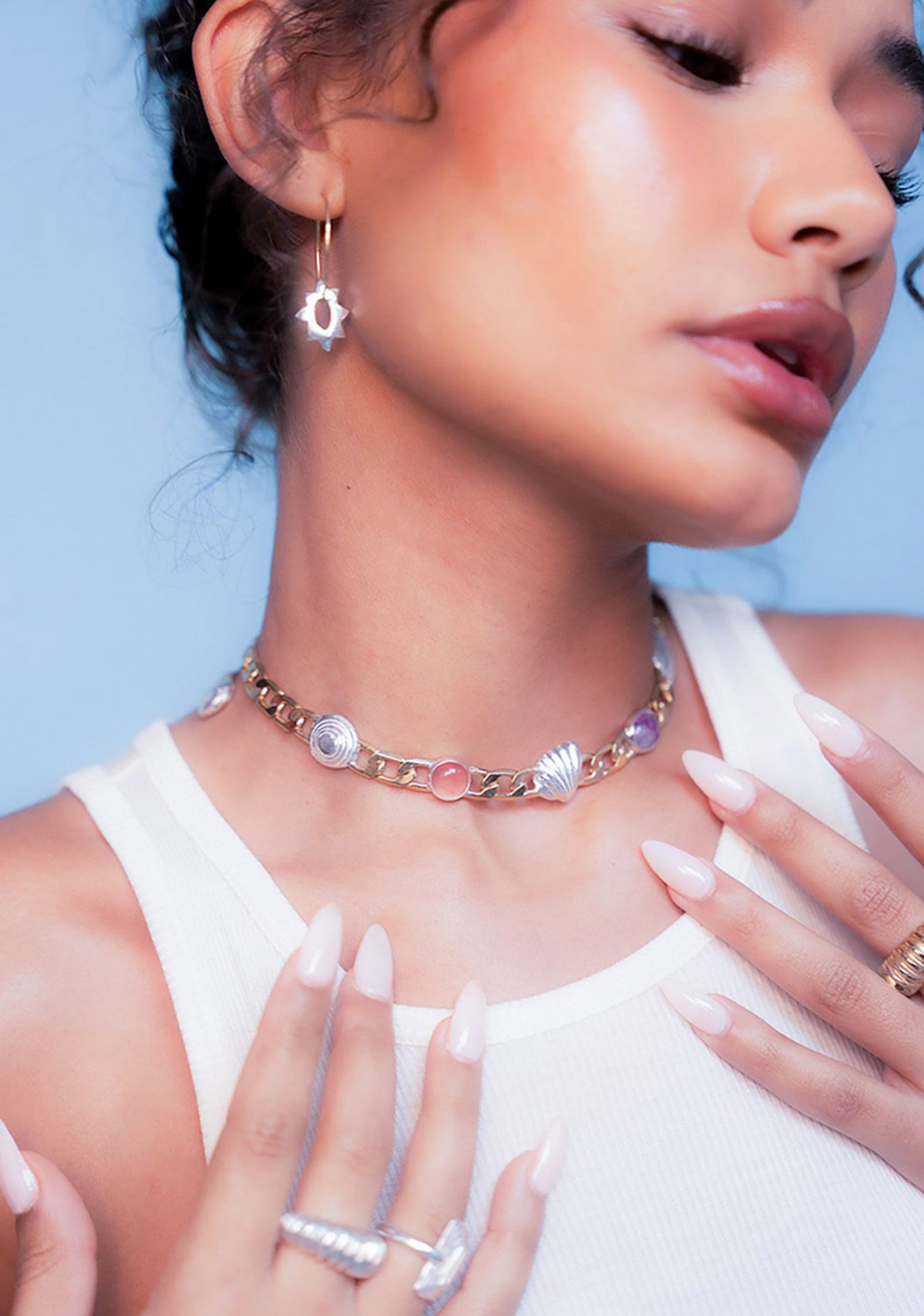 Photograph of model wearing jewellery collection including earrings, rings and a necklace