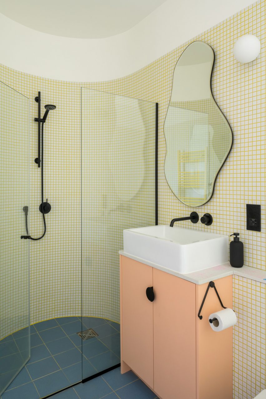 Foto de un baño con azulejos blancos y lechada amarilla.
