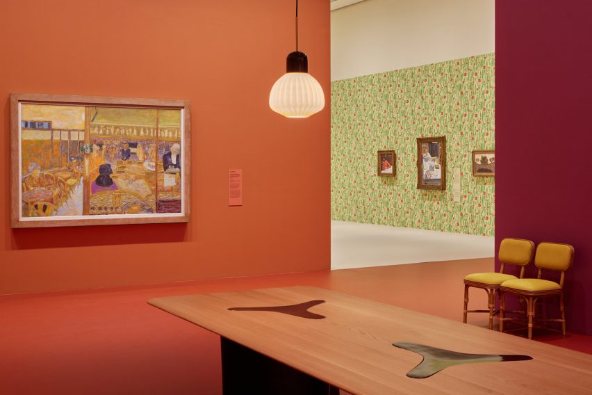 Orange-red gallery space with a wooden table in the foreground