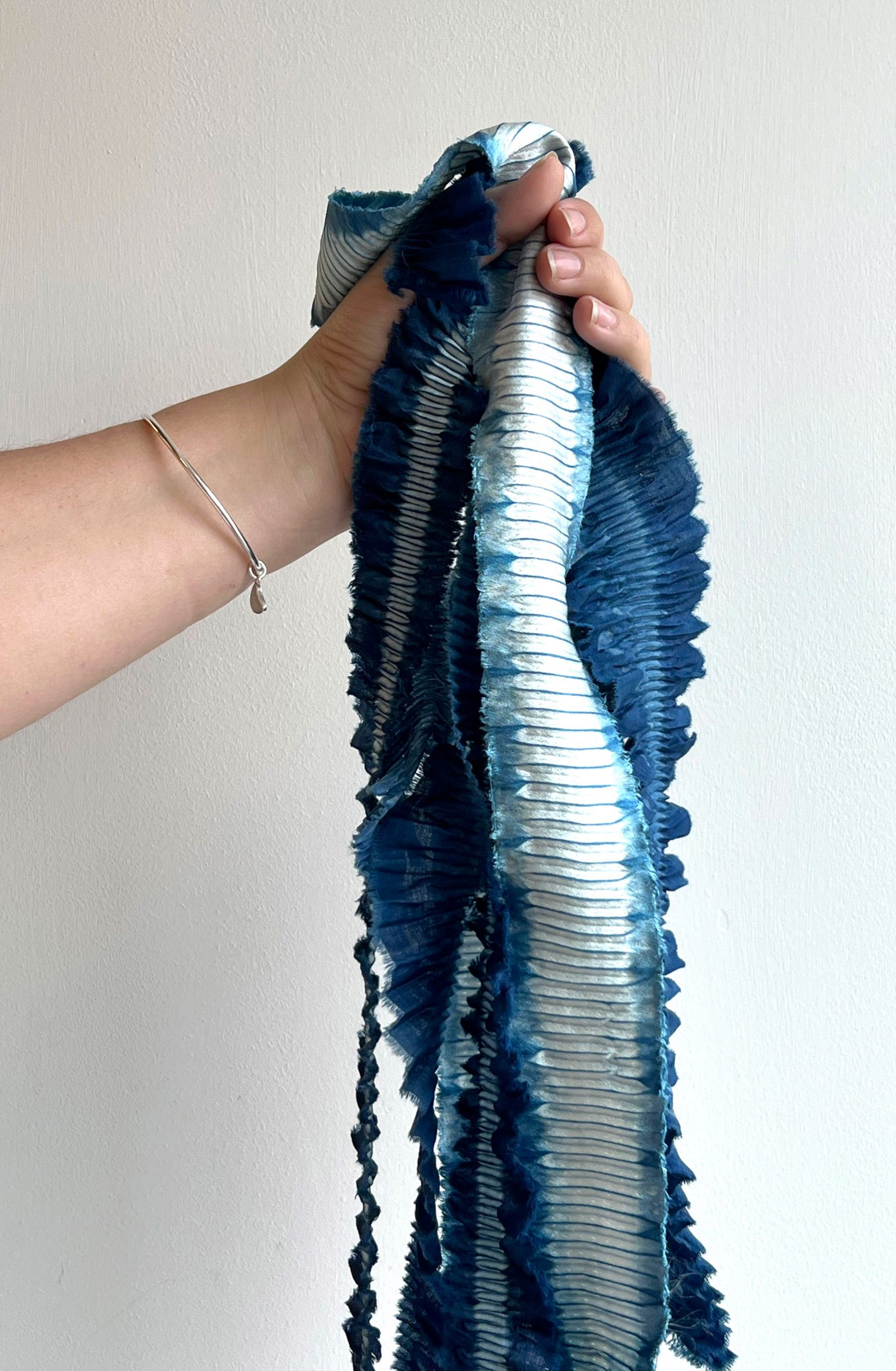 Hand grasping blue and white crimped textile