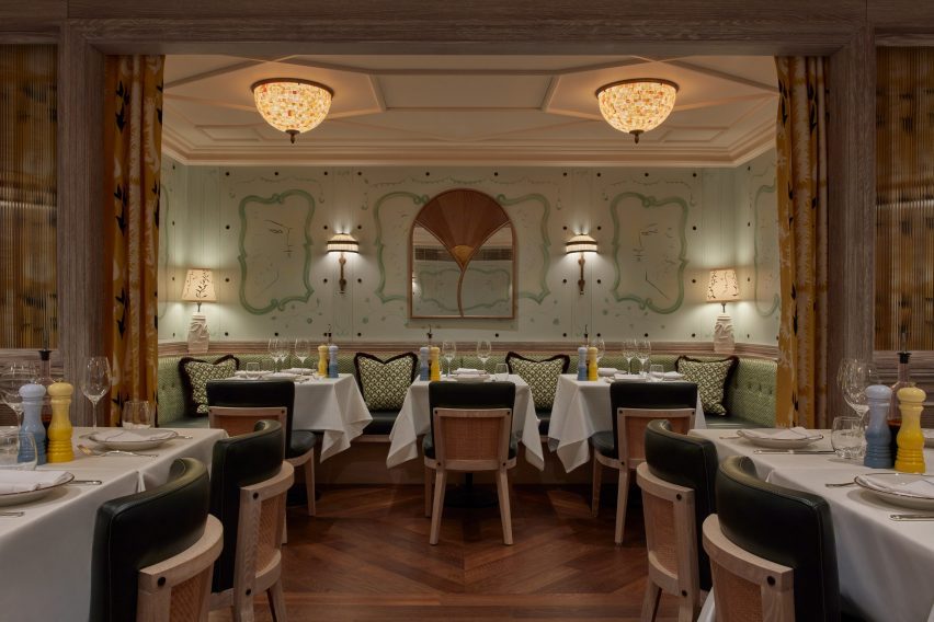 Socca restaurant interior with green-hued walls, ornate ceiling mouldings and hand-painted murals