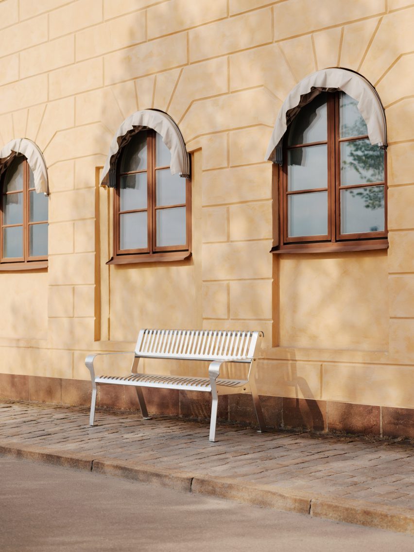 Фото легкой стальной скамейки на улице европейского города на фоне старого здания