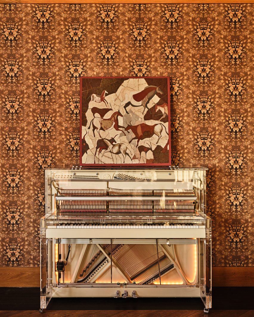 Translucent standing piano against a wallpaper-covered wall