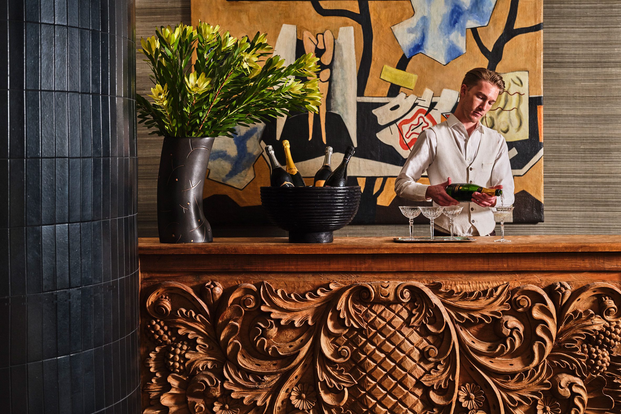 Bartender pours drinks behind an intricately detailed wooden bar