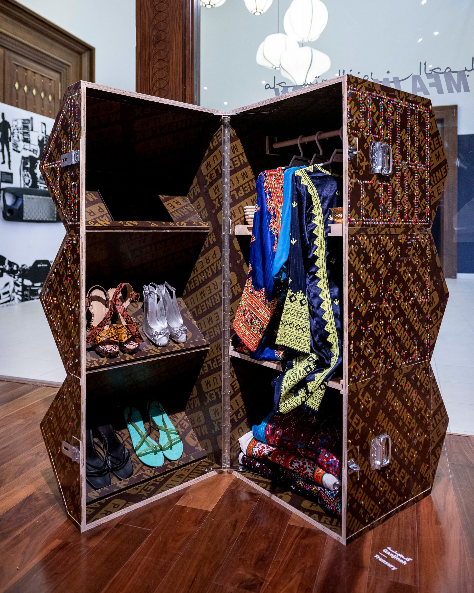 A wooden cabinet with three shelves filled with shoes and clothing