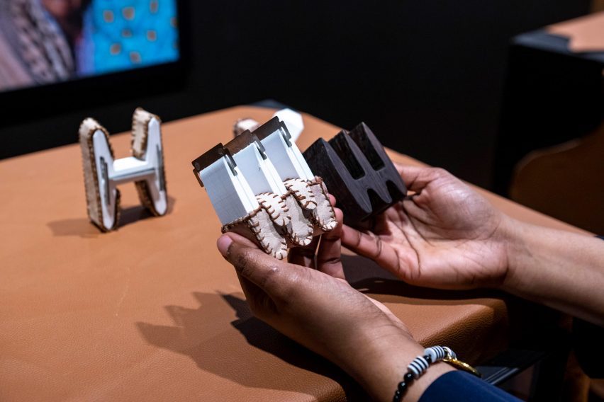A Virginia Commonwealth University student holding small H-shaped wooden models