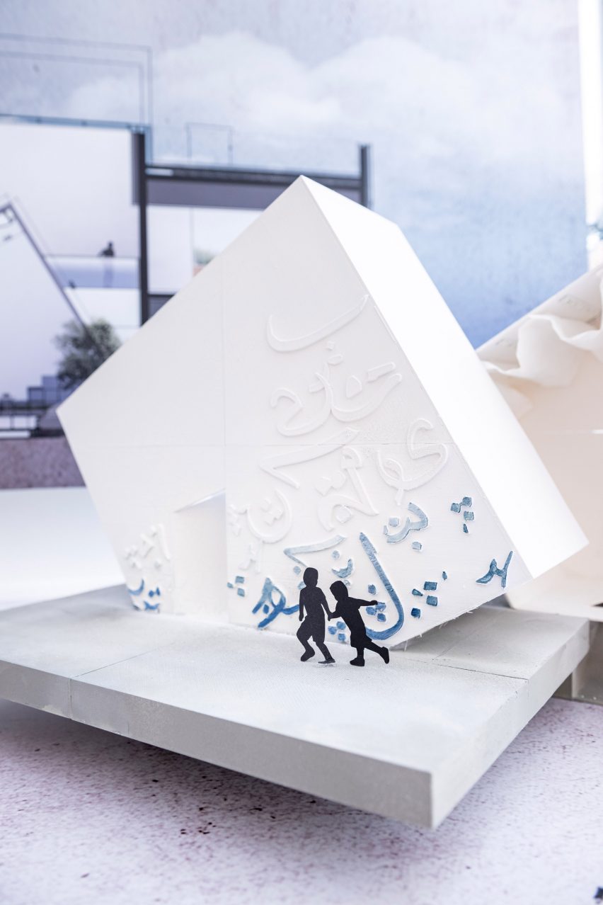 Architectural model of a tilted white cube with Arabic lettering on the surface presented on a plinth at Virginia Commonwealth University