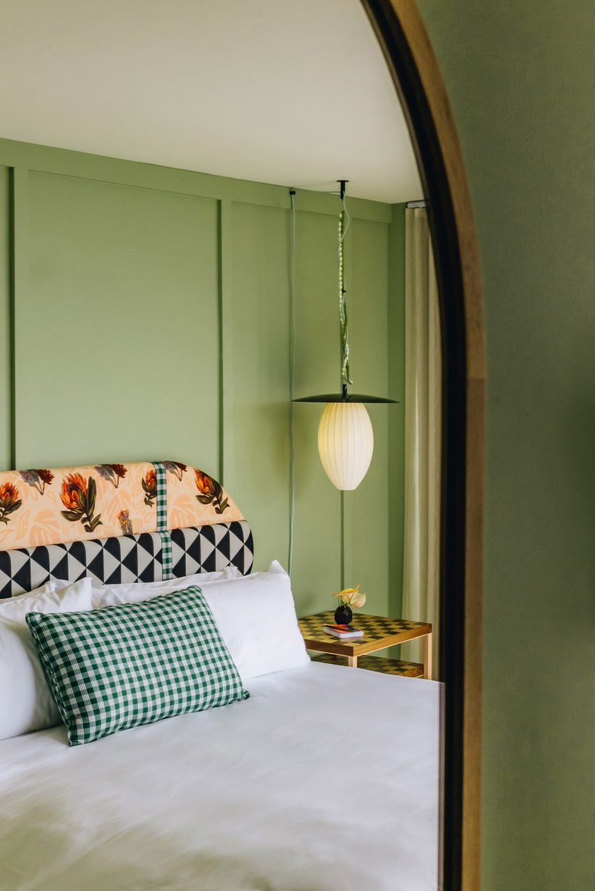 Habitación de invitados pintada de verde reflejada en un espejo