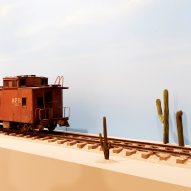 A model train on a rail track with cacti