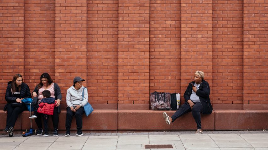 Photo of people sat by a brick wall