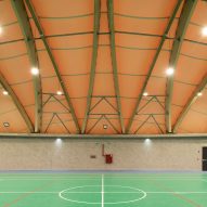 A sports facility with wooden arches and a bright green court
