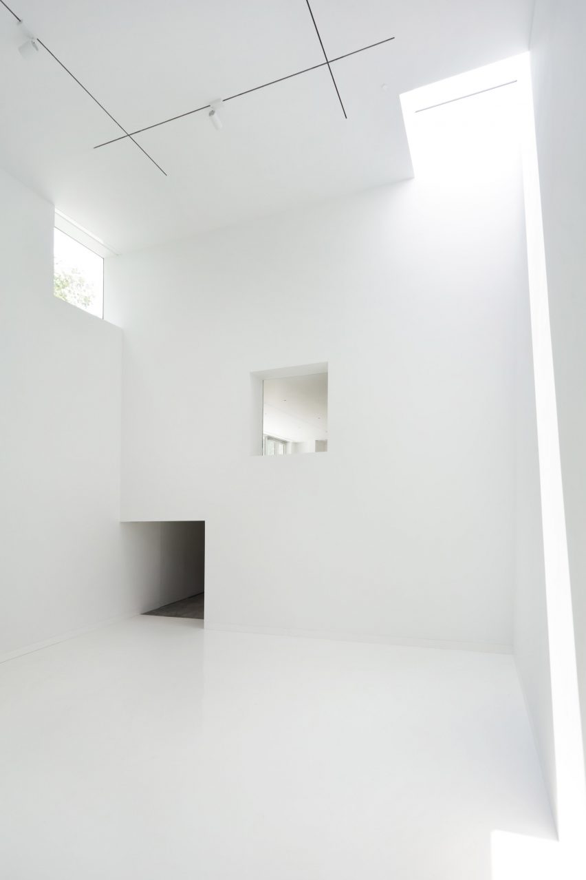 Habitación interior blanca con luz que se filtra a través de ventanas cuadradas