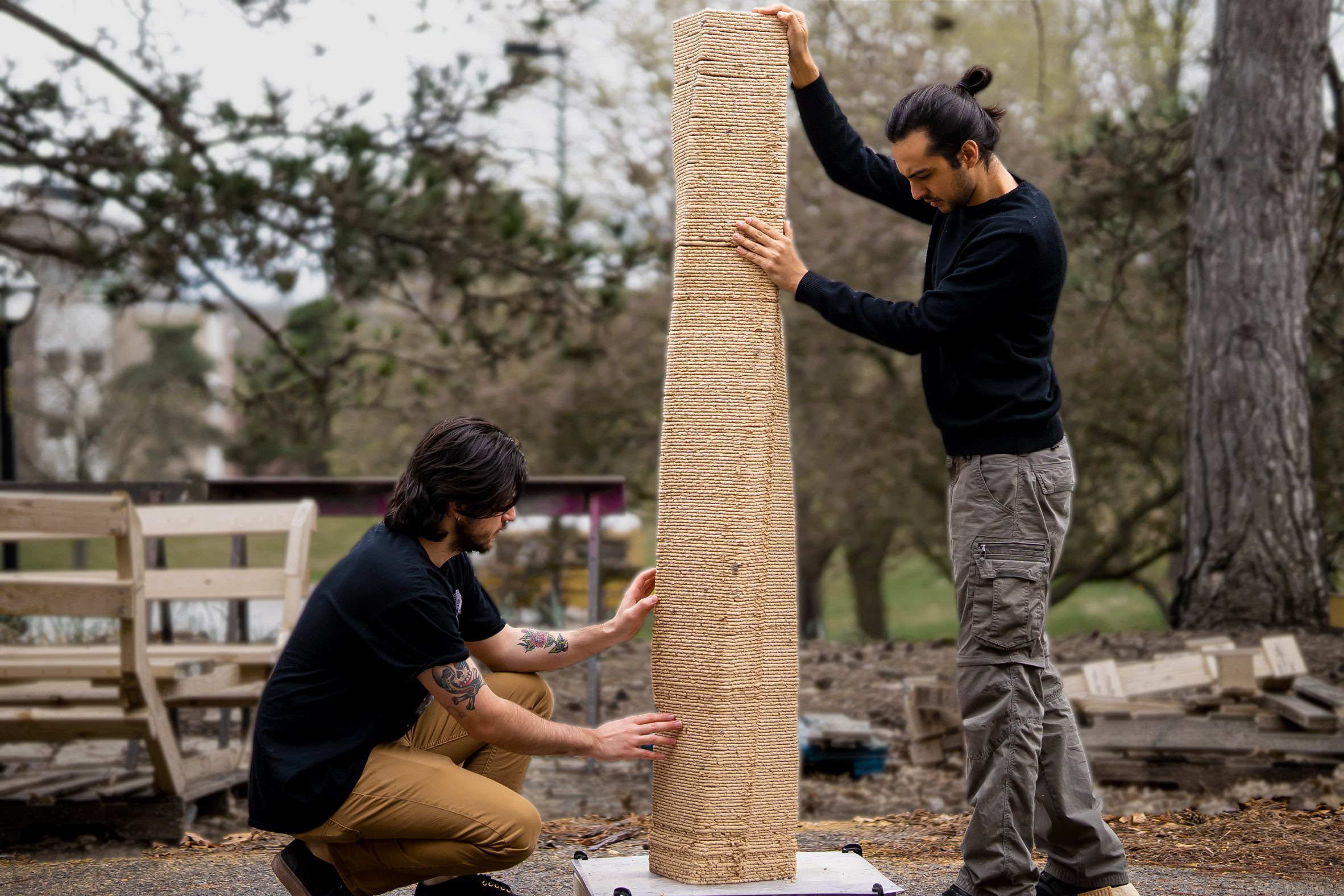Two people hold a 3D-printed sawdust column