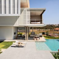 A contemporary home overhanging a pool and large patio