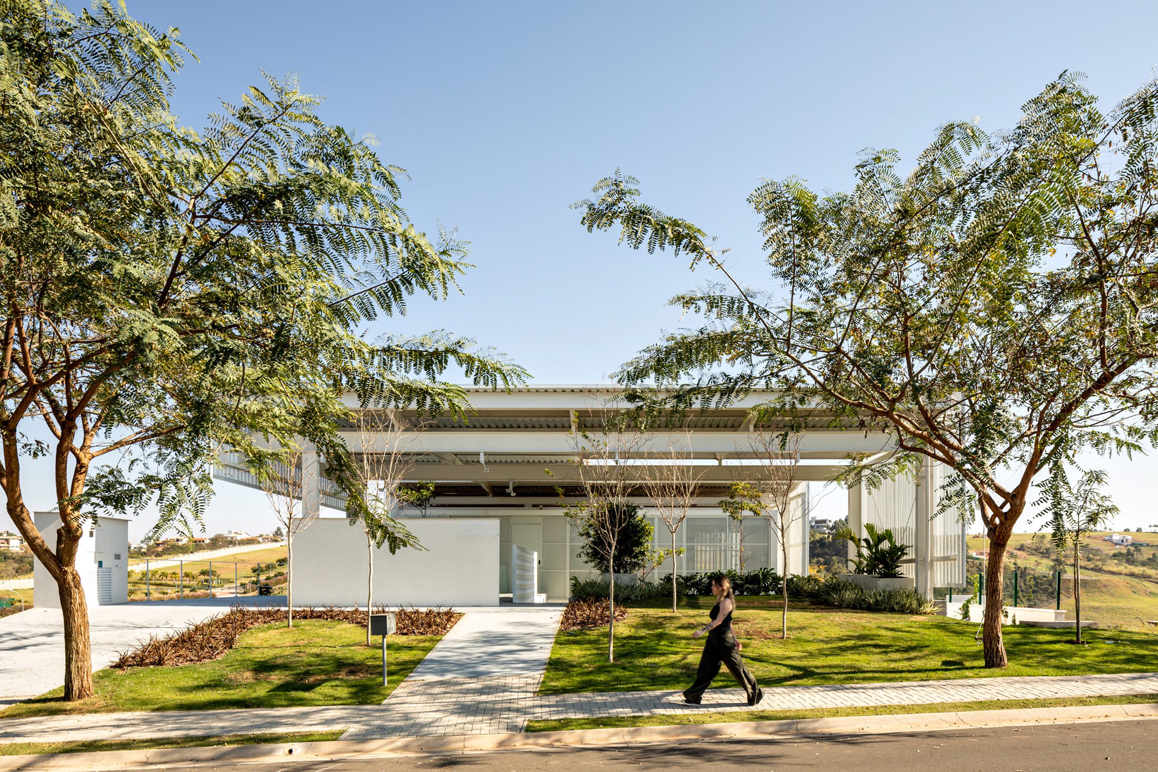 A person walking in front of a contemporary white, residence in Brazil