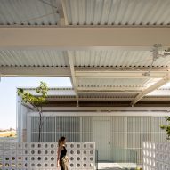A person walking underneath the corrugated metal ceiling of a residence in Brazil
