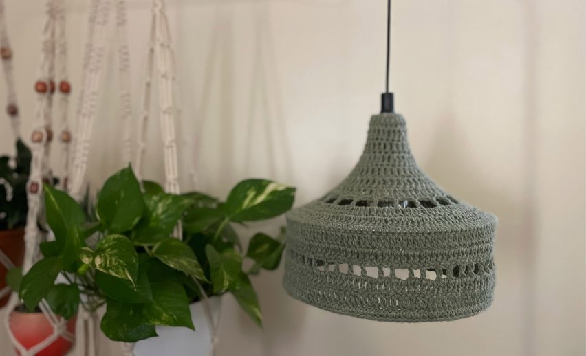 Green crochet lamp shade hanging beside plants