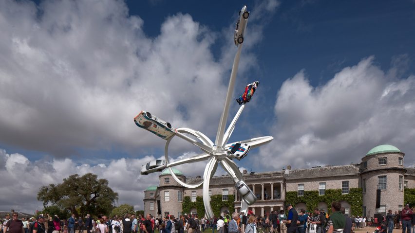A white steel sculpture with cars attached