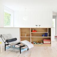 A room with white walls, wood flooring and built-in wooden storage