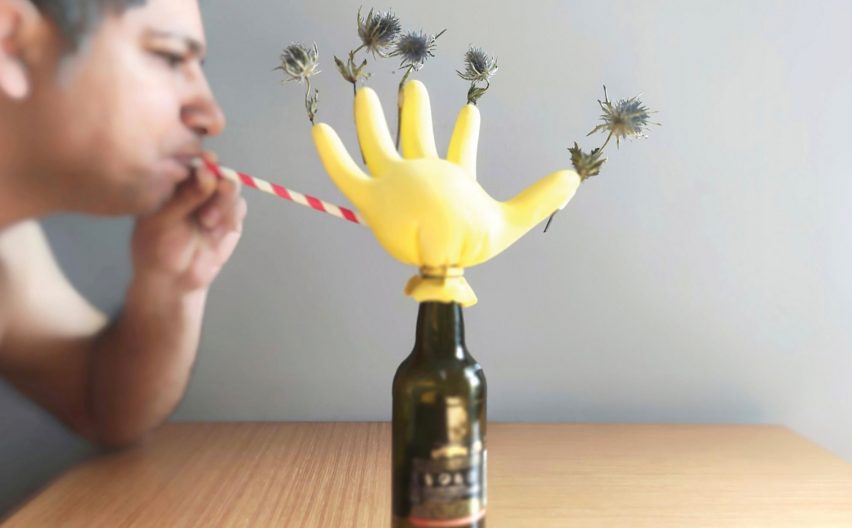 A man blowing air through a straw into a rubber glove that is tied around a glass bottle