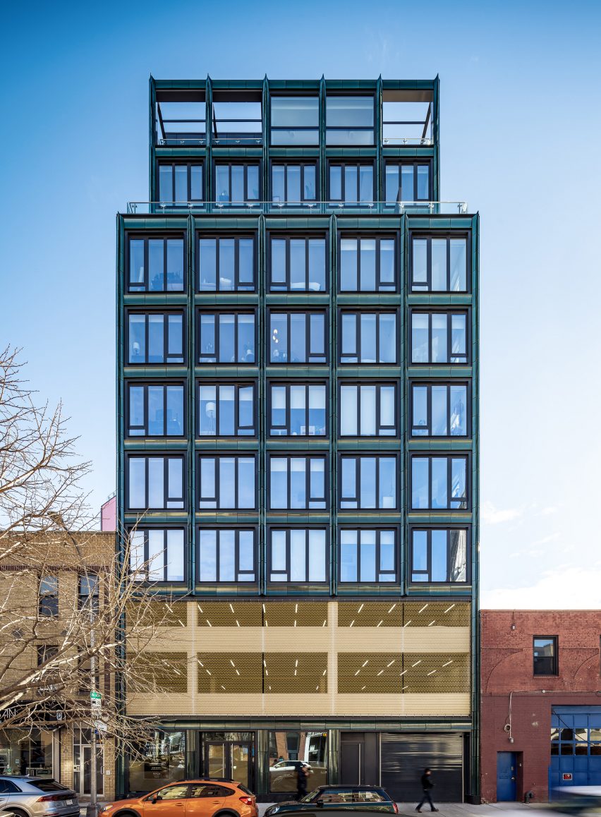 Edificio revestido con baldosas de terracota, grandes ventanas enrejadas y malla de bronce en 50th Avenue en Long Island City