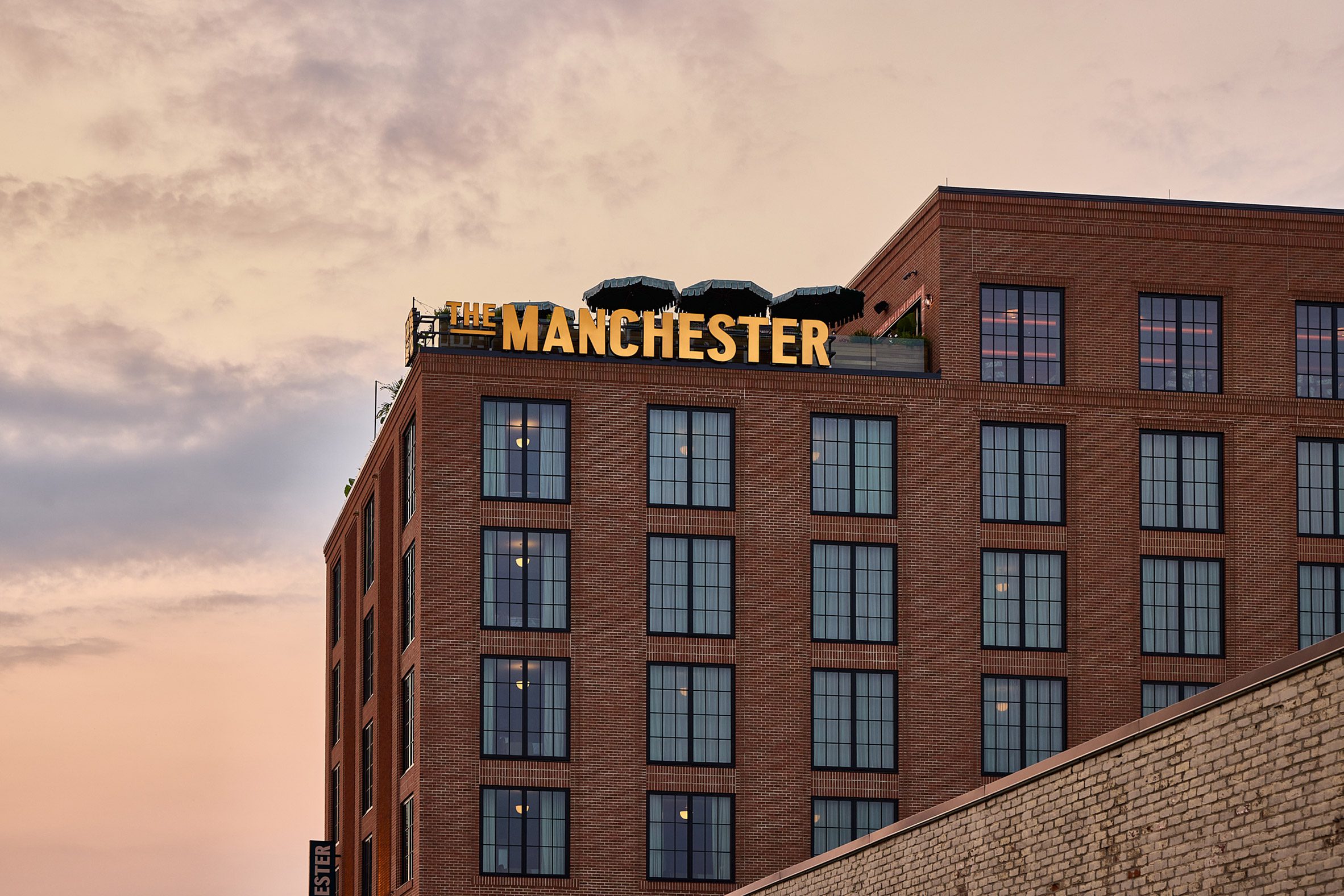 Exterior view of brick building with "The Manchester" sign in yellow