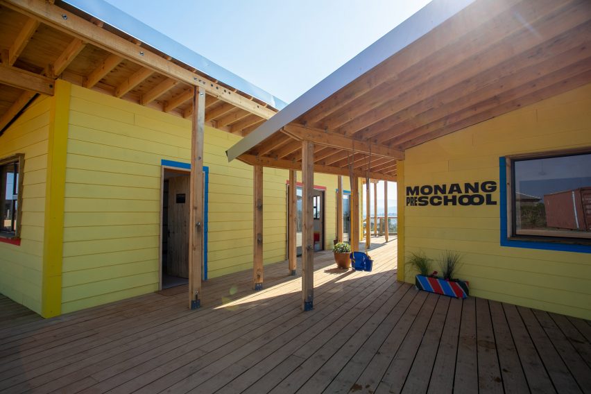 Photograph of Monang Preschool showing the timer roof structure and yellow walls with black lettering