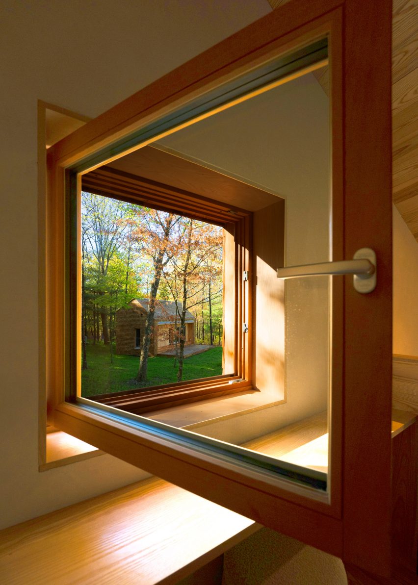 An open window with a view of a cabin in the woods