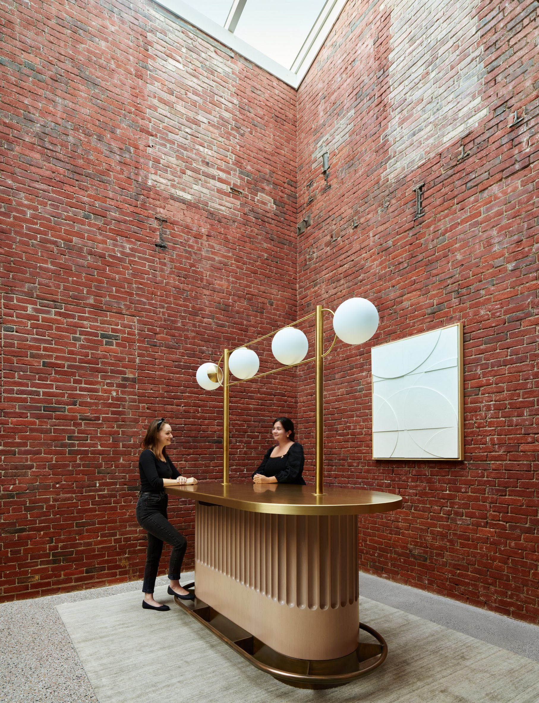 Brass counter surrounded by tall brick walls beneath a skylight