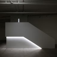 The blocky, white staircase with strip lighting that leads into a dark basement