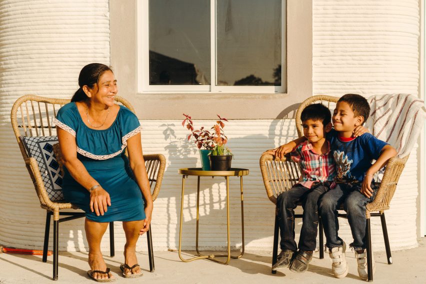 Picture of women and two young boys sitting outside a house