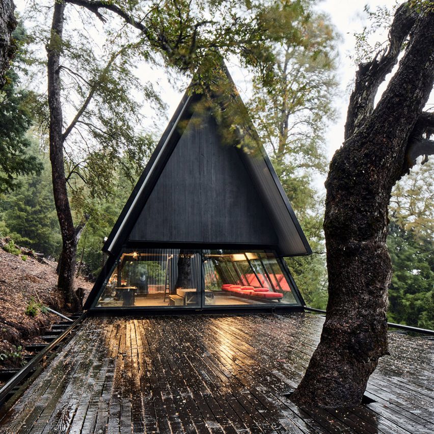 A-frame black wood house on timber decking in a forest