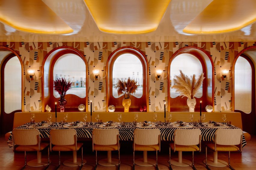 Private dining rooms with a long table below patterned wallpaper and fritted glass panels