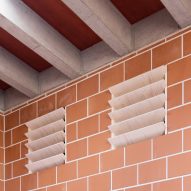 Air vents on a terracotta brick wall with concrete roof beams