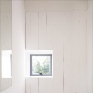 A small window in a wall clad with wooden panels