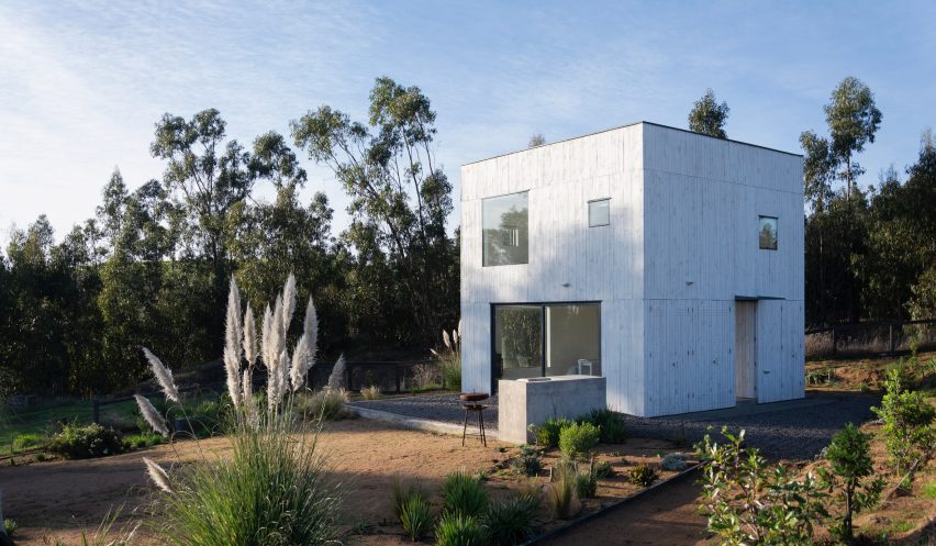 A white cube-shaped house with a garden