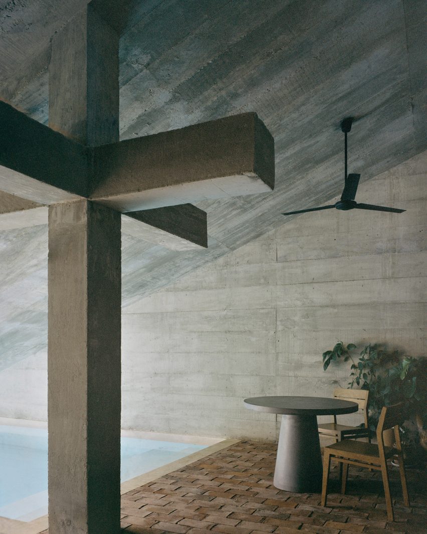 Table and chairs next to a pool underneath a slanting roof