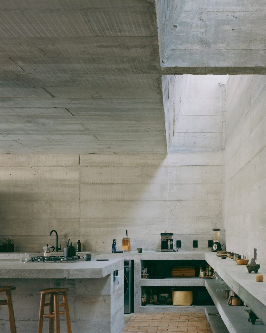 A kitchen with made of concrete with a skylight along a wall