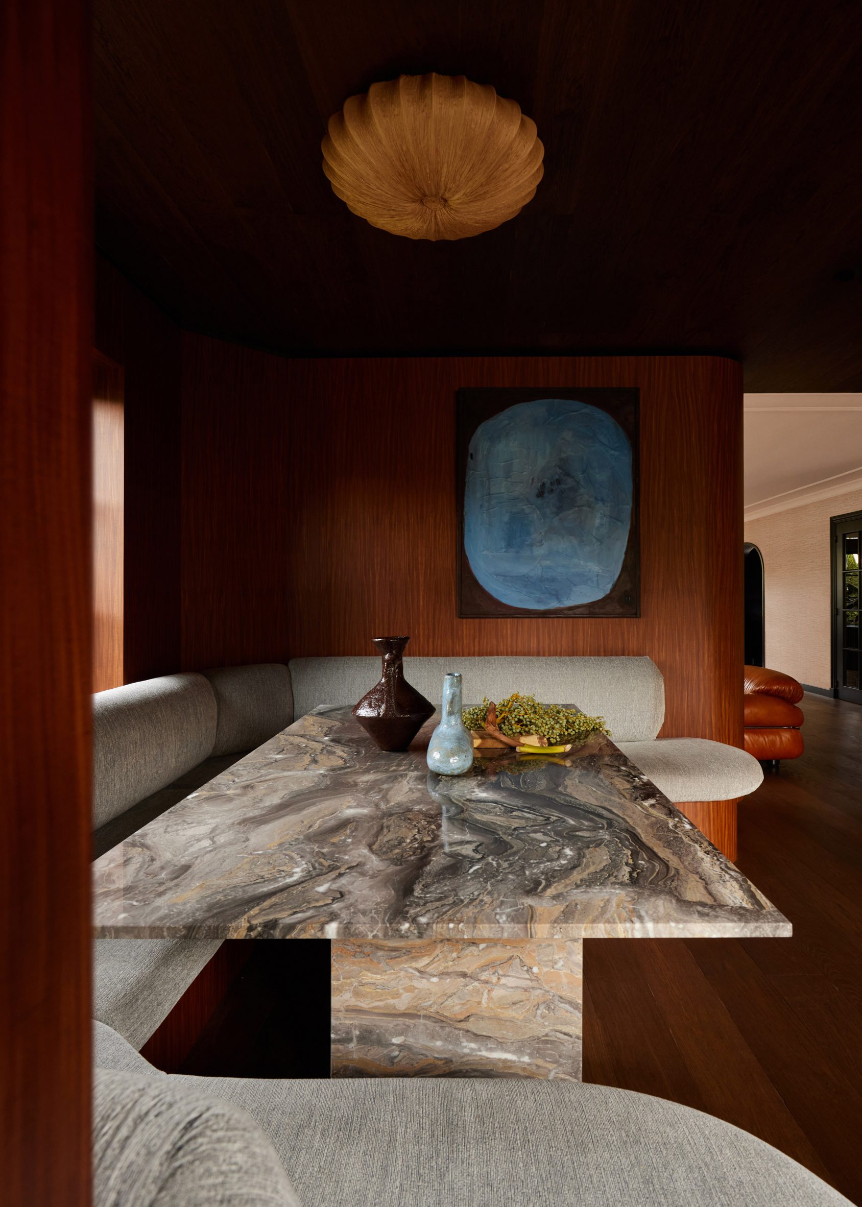 Wood-clad seating nook with upholstered seating and a marble table by DAB Studio