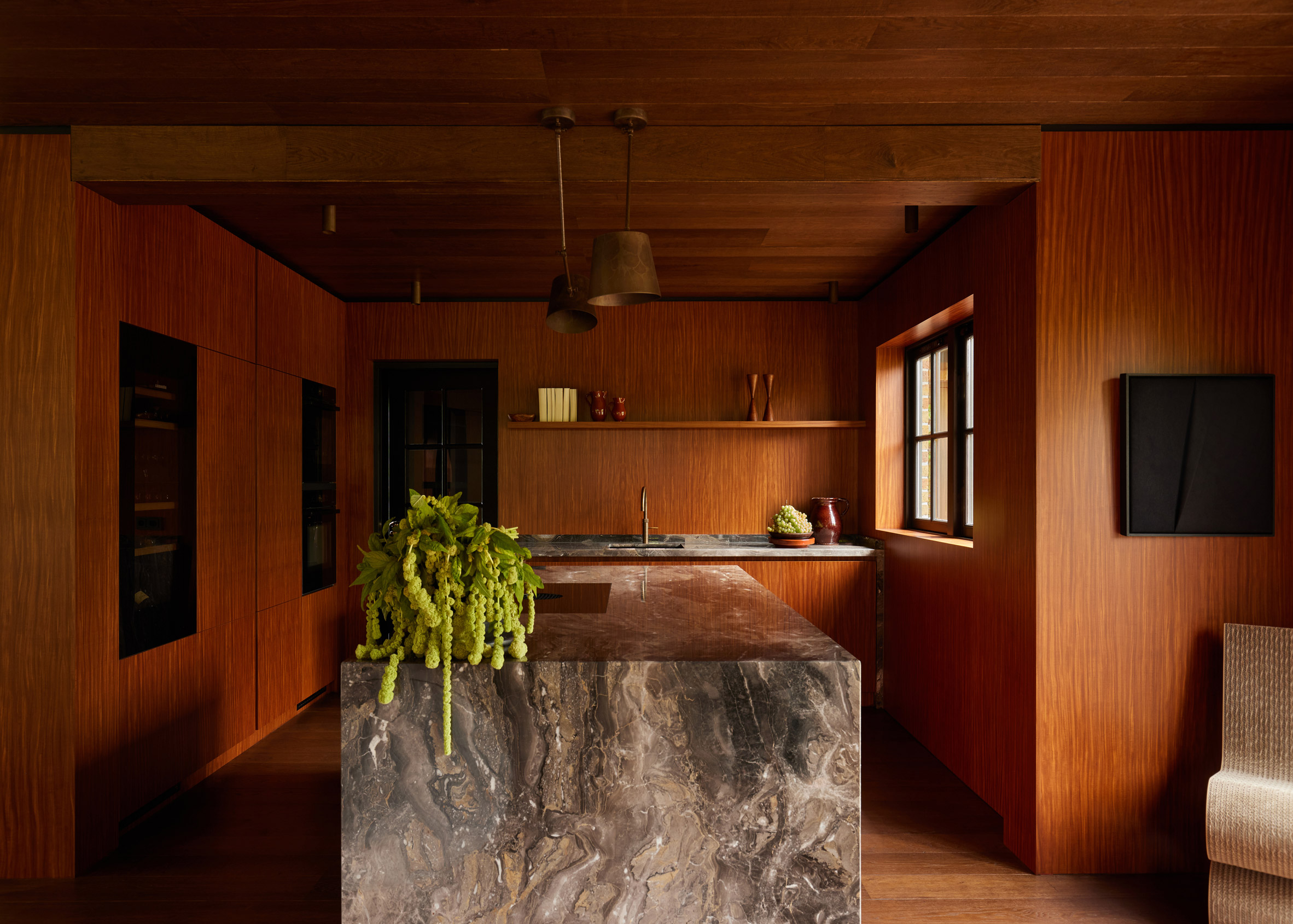 Wood-lined kitchen interior with a marble island by DAB Studio