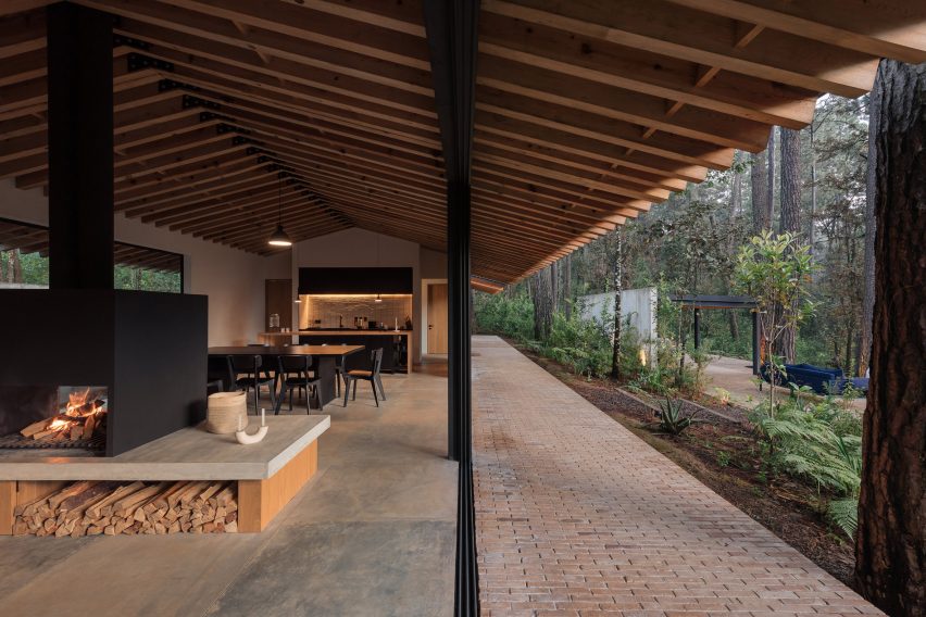 Open-plan living interior with stone floors, timber pitched roof and glazed walls leading outside