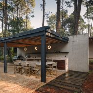Outdoor kitchen with a black timber roof canopy by Estudio Atemporal