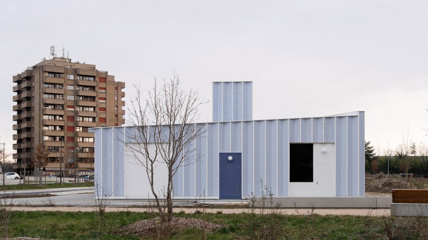 Blue timber workshop in a garden near residential towers by Cabinet