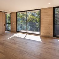 Interior space with board-formed concrete walls, wood flooring and glass doors leading to balconies