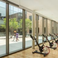 indoor gym with bike machines next to windows overlooking a courtyard