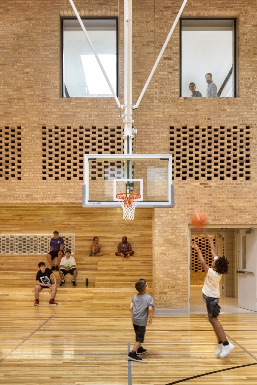 People playing basketball in an indoor court with exposed brick walls