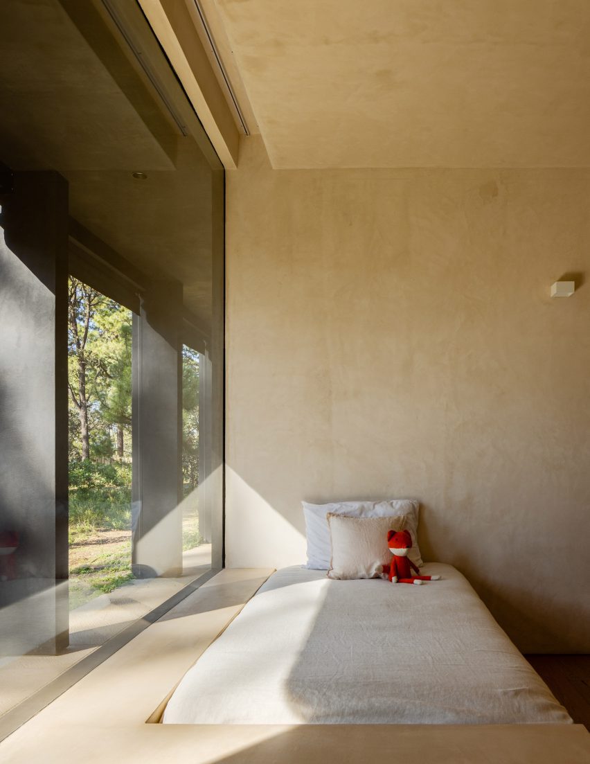 Una cama en una habitación con una ventana grande y paredes con paneles de madera clara