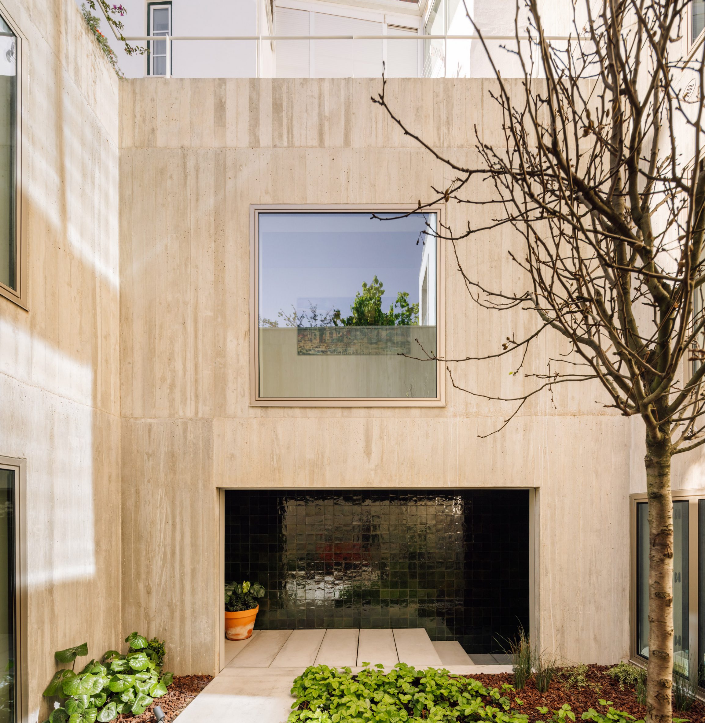 Courtyard in a concrete house with green-tiled loggia by Bak Gordon Arquitectos